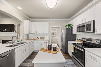 A modern kitchen with white cabinets and stainless steel appliances.